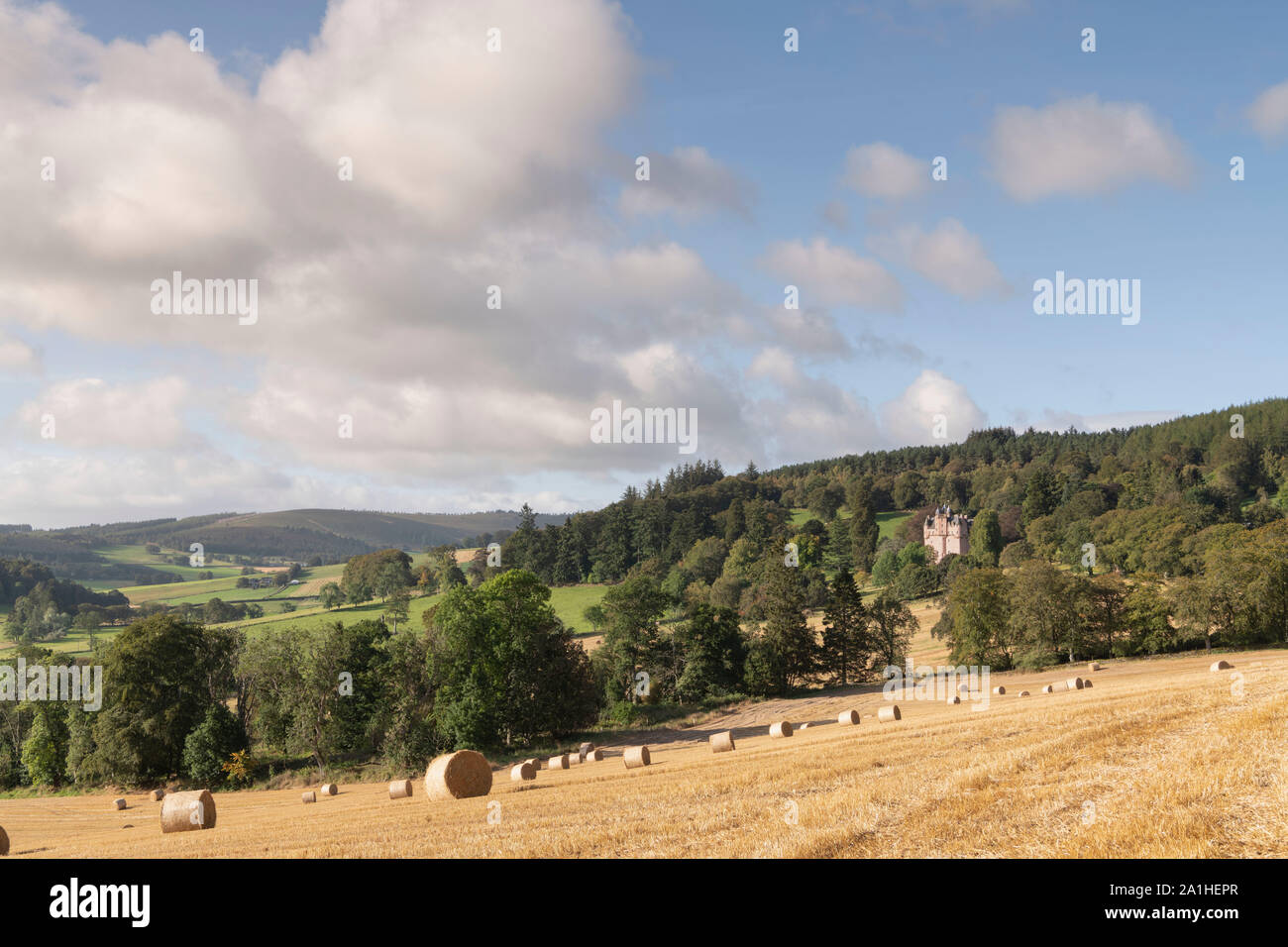 Une Vue sur campagne vallonnée, dans l'Aberdeenshire, avec un champ de bottes de paille et de Craigievar Castle niché sur une colline boisée surplombant les terres agricoles Banque D'Images