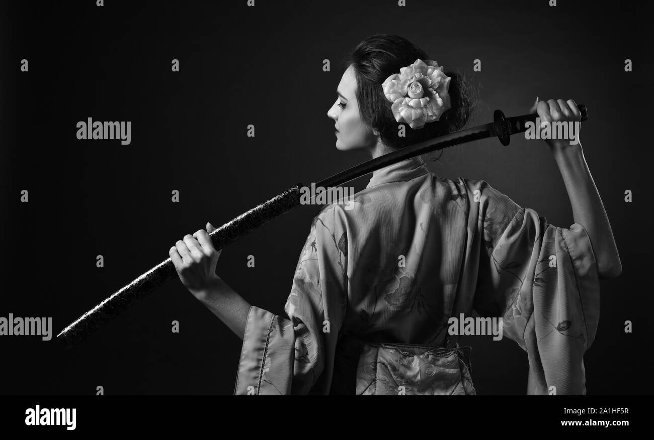 Jolie femme en kimono traditionnel japonais avec katana ( épée japonaise). Belle jeune femme aux cheveux parfaits et un miroir. noir et blanc. Banque D'Images