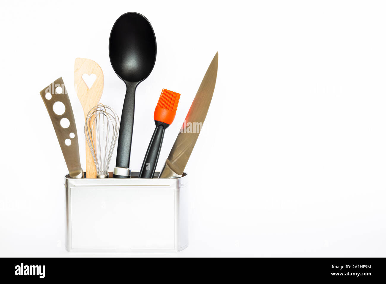Assortiment d'ustensiles et outils de cuisine dans une boîte de métal de couleur argent carré avec copie espace sur fond blanc Banque D'Images