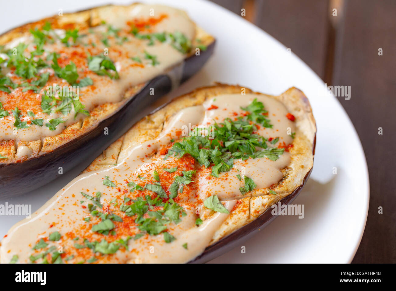 L'aubergine cuite au four avec sauce tahini vegan, poudre de poivre et persil ghost Banque D'Images