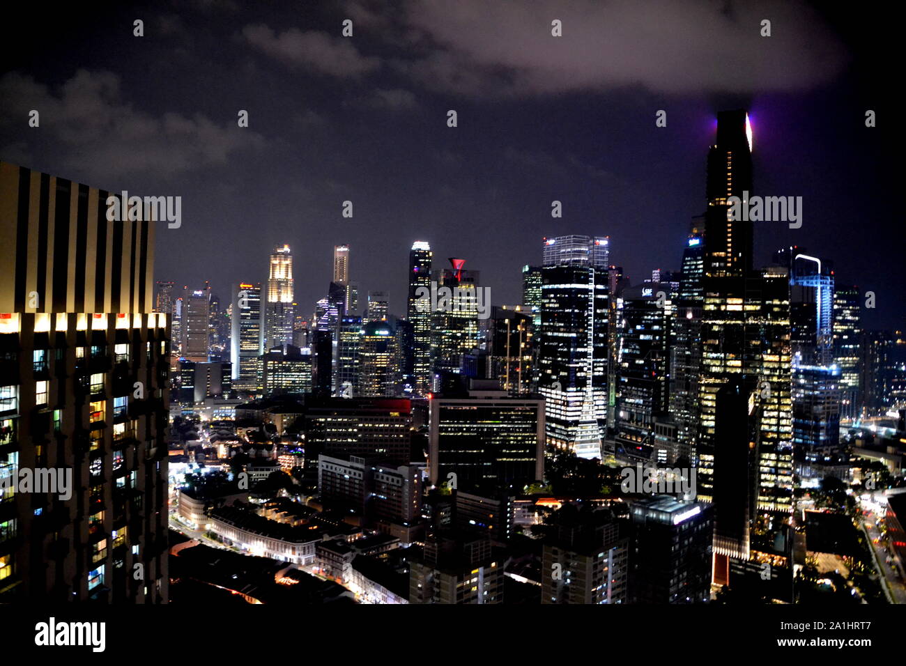 Skyline de Singapour de nuit avec des gratte-ciel illuminés et nuageux ciel sombre Banque D'Images