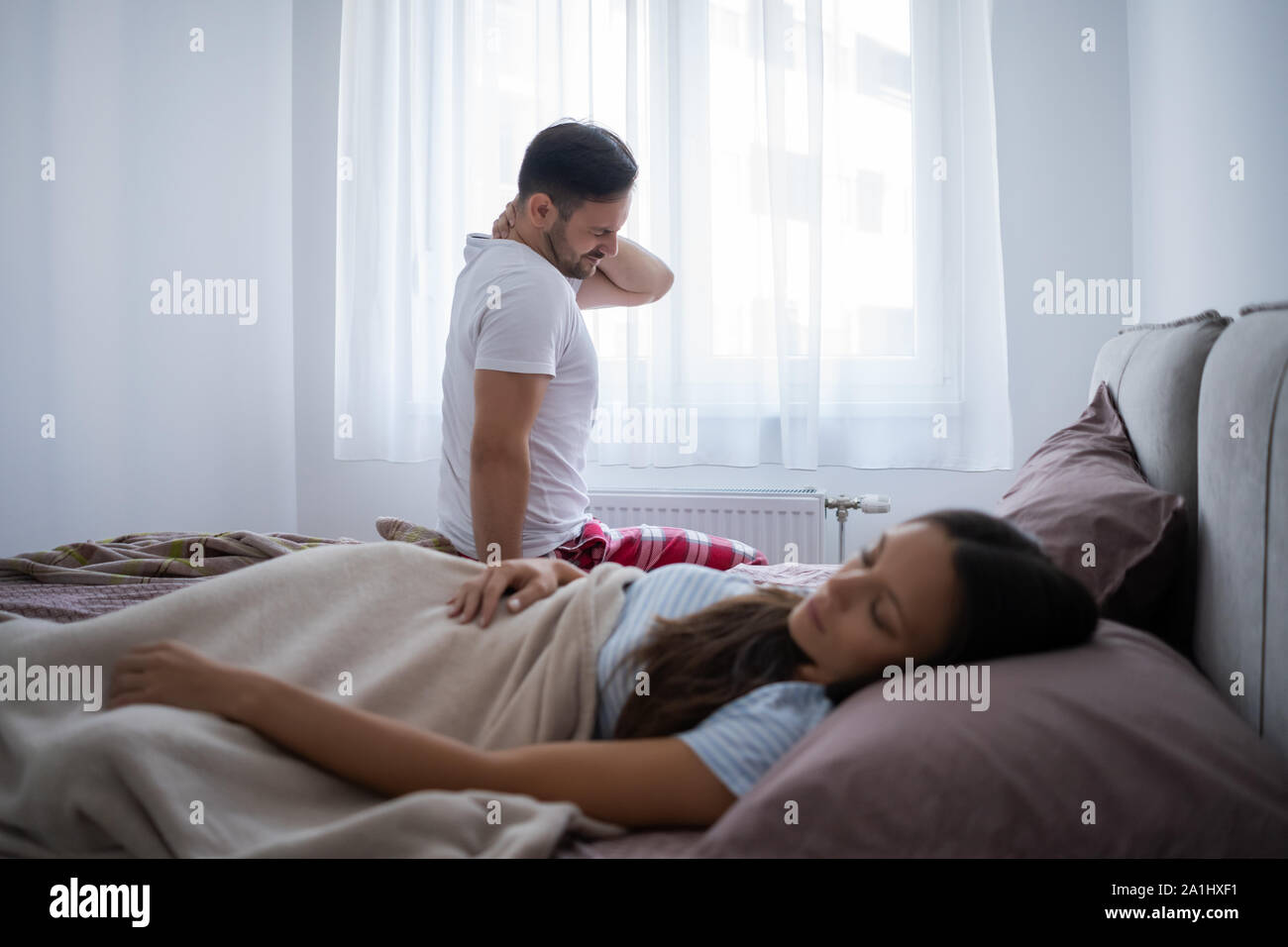 Jeune couple est se réveiller le matin. L'homme a de la douleur dans le cou. Banque D'Images