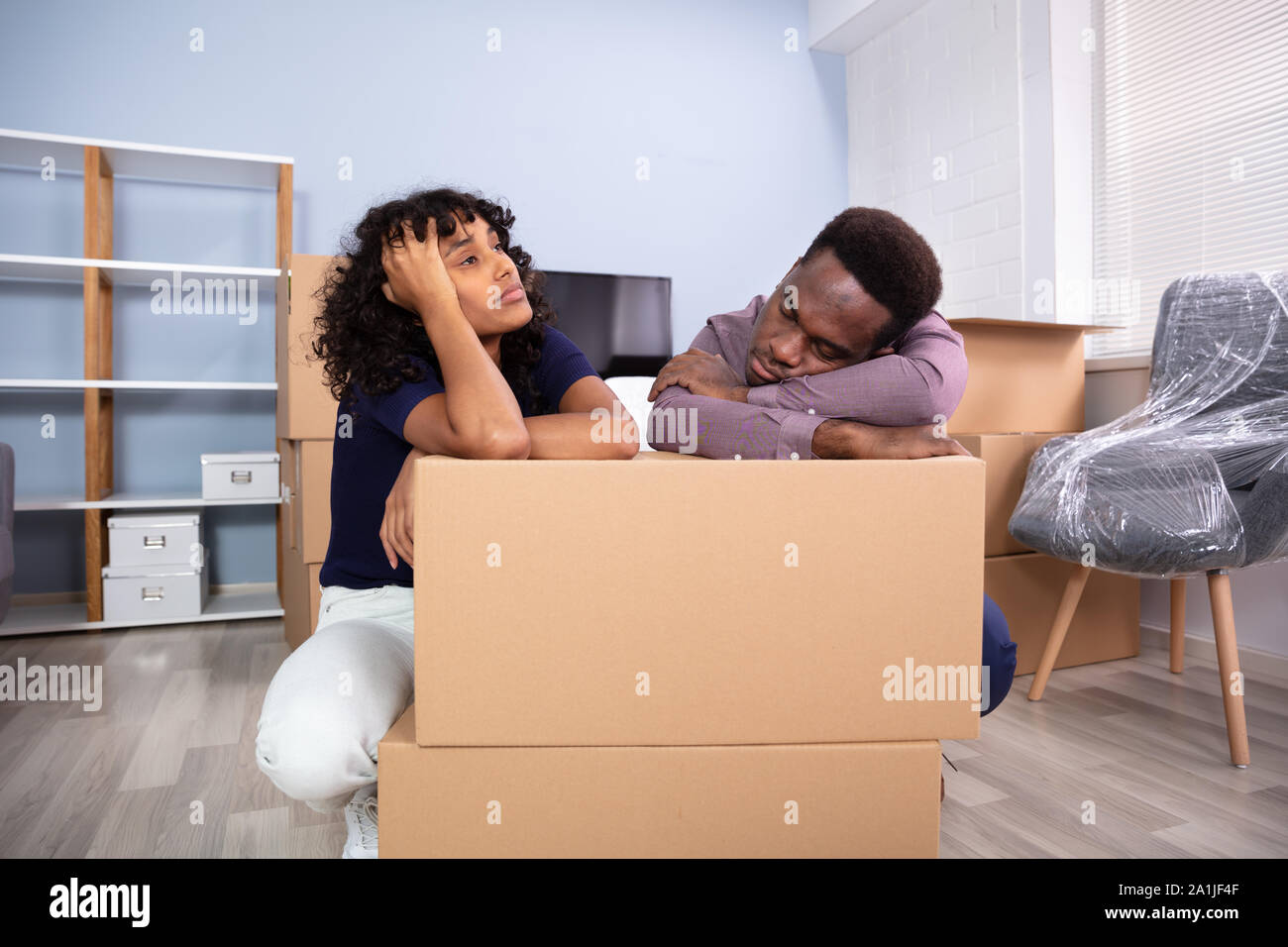 Souligné Couple Sitting près de boxes in New Home Banque D'Images