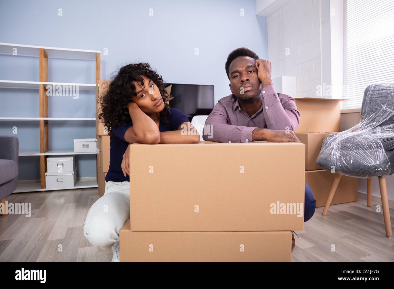 Souligné Couple Sitting près de boxes in New Home Banque D'Images