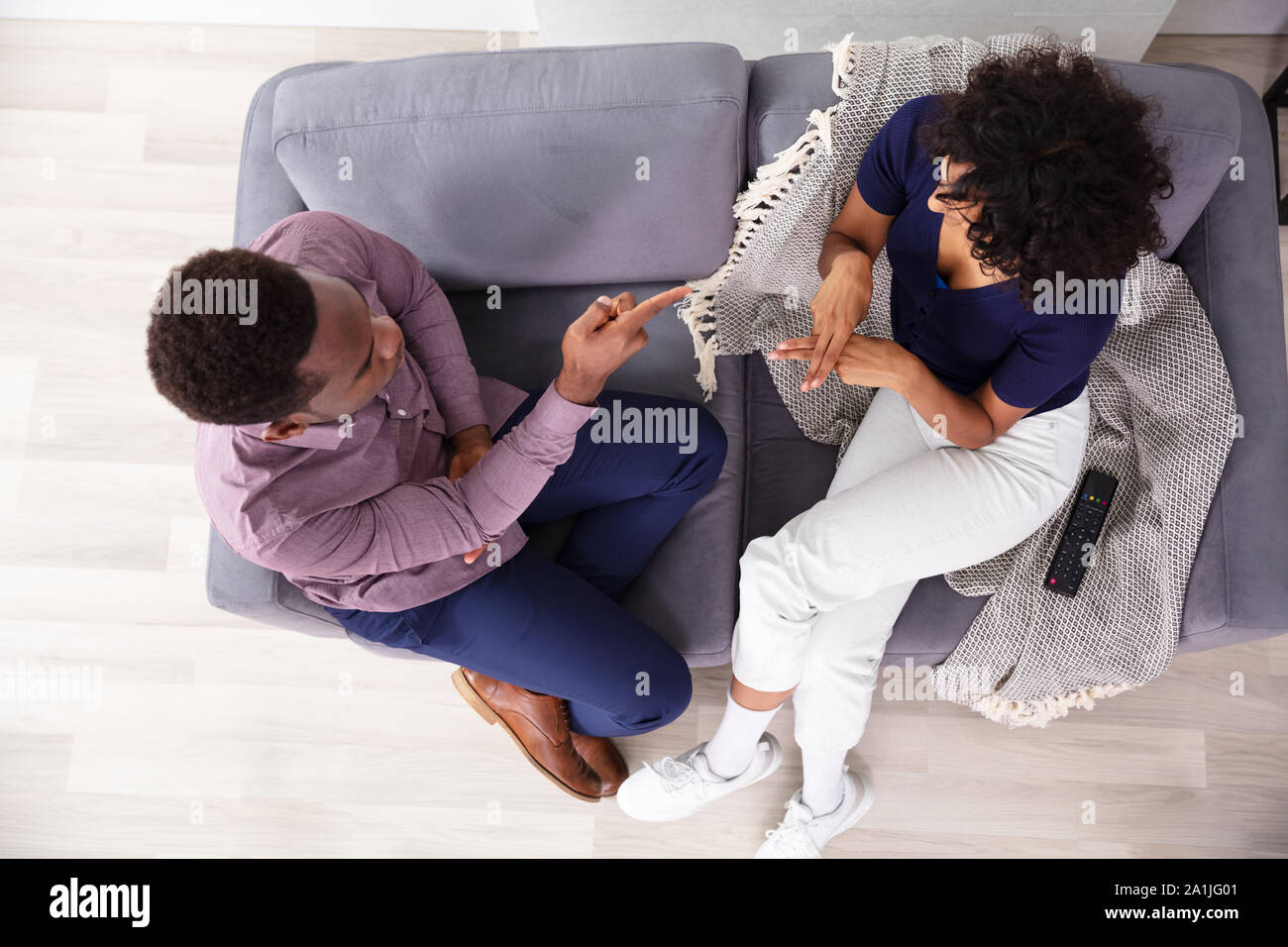 L'homme et de la femme de la communication avec les langues des signes Sitting on Sofa Banque D'Images