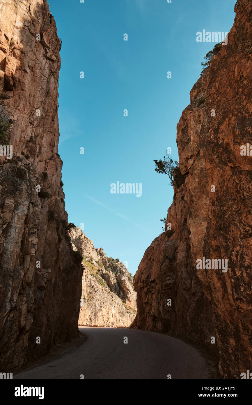 Une coupe de route à travers les rochers et falaises de granit rouge le long du site du patrimoine mondial de l'UNESCO sur le golfe de Porto dans l'ouest de la côte corse. Banque D'Images