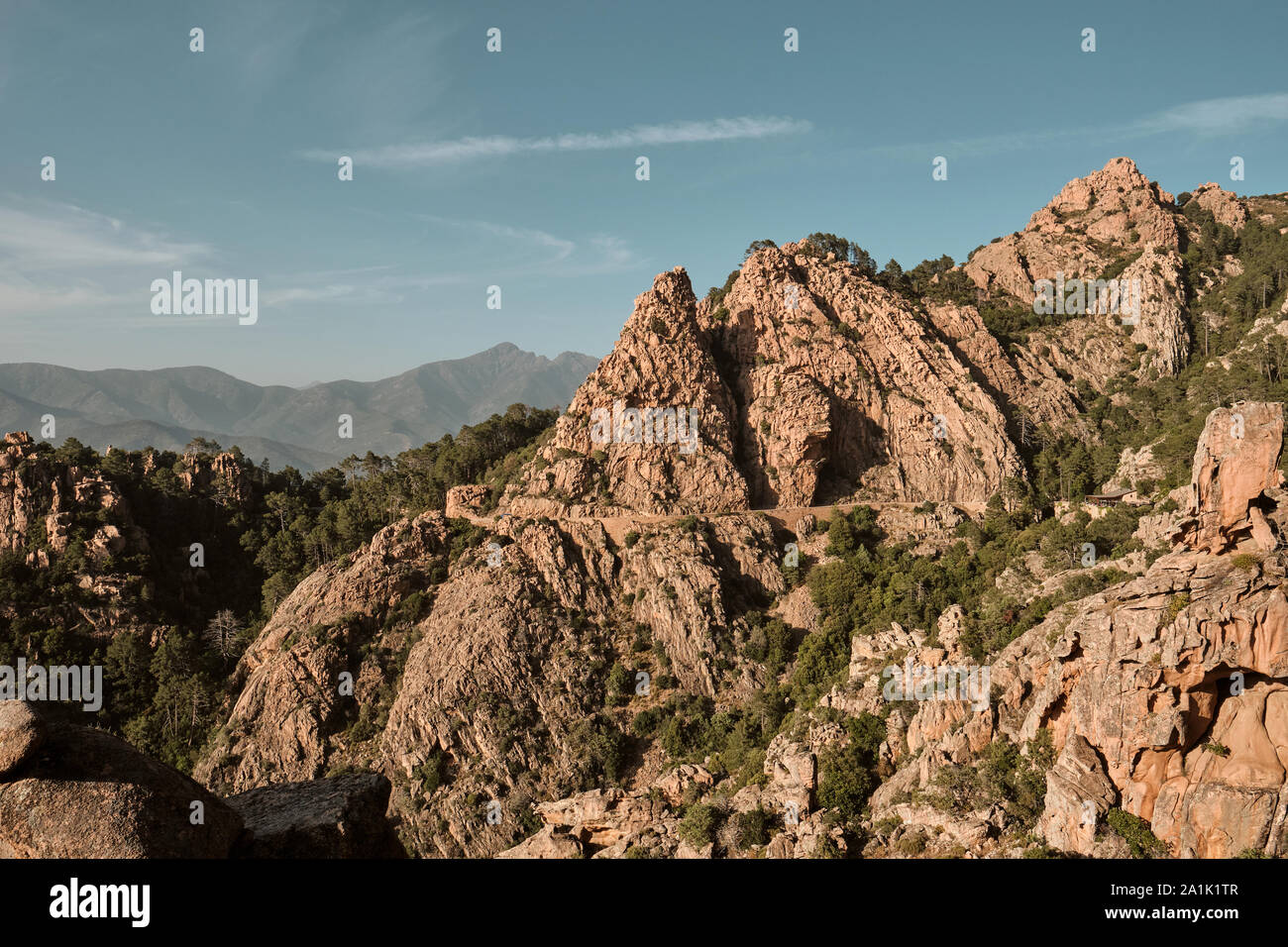 Les roches et les falaises de granit rouge et route le long du site du patrimoine mondial de l'côte de la Calanques de Piana / Golfe de Porto dans l'ouest de la Corse. Banque D'Images