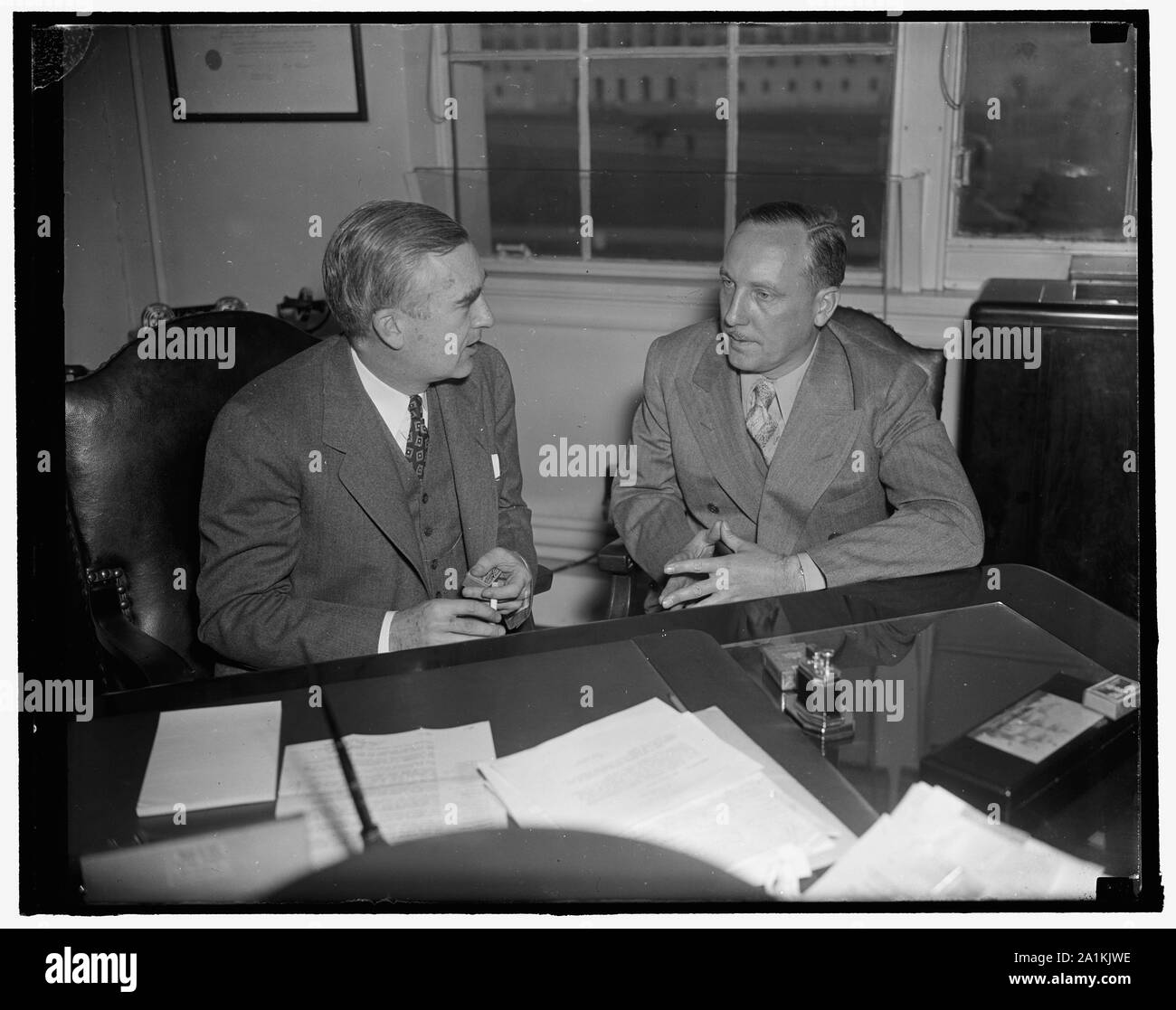 Newsreel cameraman décrit naufrage de Panay au sous-chef de la Marine. Washington, D.C., le 31 décembre. Norman Alley, intrepid newsreel cameraman qui était à bord du U.S.S. Photos de tournage de Panay tandis que la canonnière a été bombardé par les Japonais dans la rivière Yangtze, le 12 décembre, décrivant son expérience aujourd'hui pour le sous-secrétaire de la Marine Charles Edison, (à gauche) Alley a été interrogé par des fonctionnaires de la Marine suite à la projection des photos au ministère de la Marine, 12/31/37 Banque D'Images