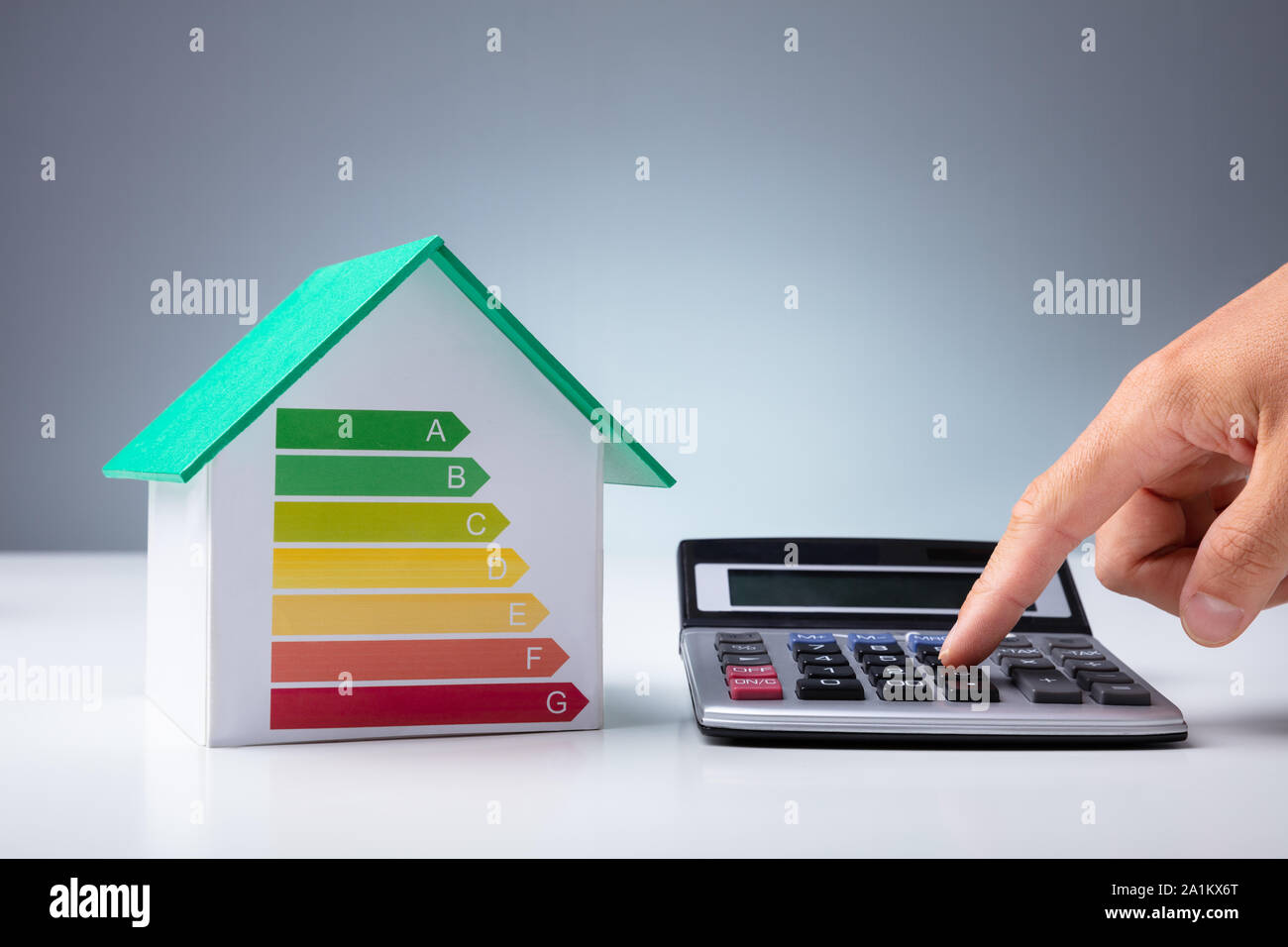 Maison miniature montrant le taux d'efficacité énergétique près de personne utilisant calculatrice sur 24 Banque D'Images
