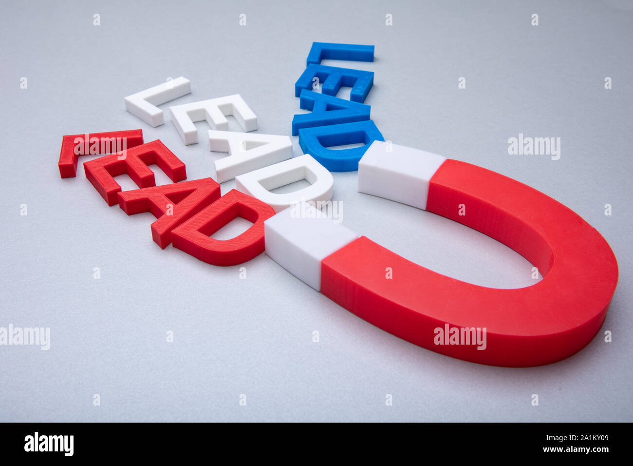 Person's Hand Holding Horseshoe aimant qui attire les câbles de couleur des lettres sur fond blanc Banque D'Images