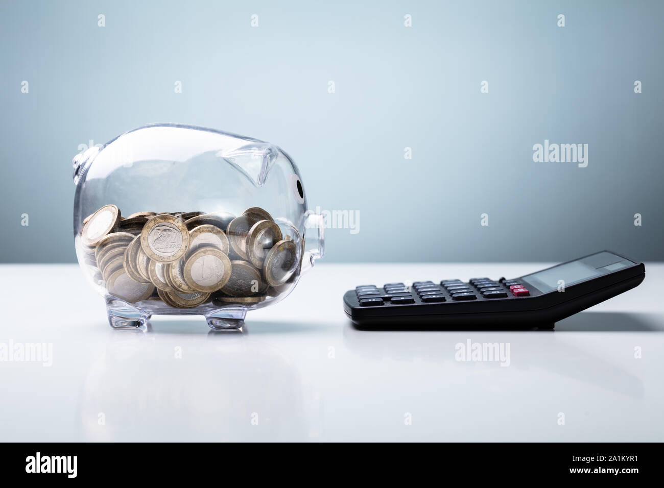 Tirelire transparente avec la calculatrice disposés sur le tableau blanc Toile Bleu contre Banque D'Images