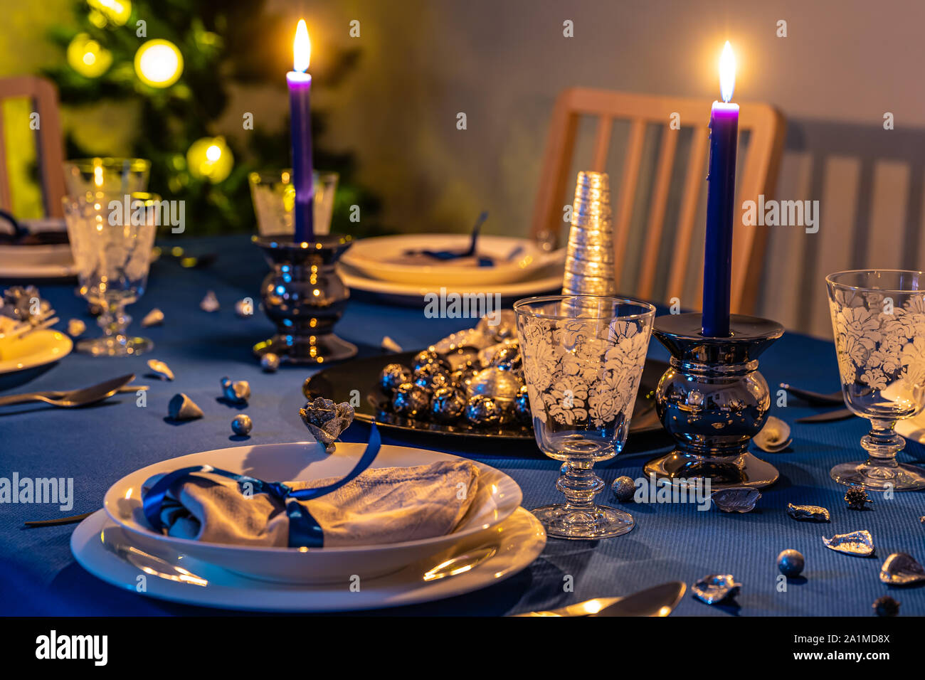 Réglage de la table de Noël avec arbre de Noël en arrière-plan à la lumière des bougies Banque D'Images