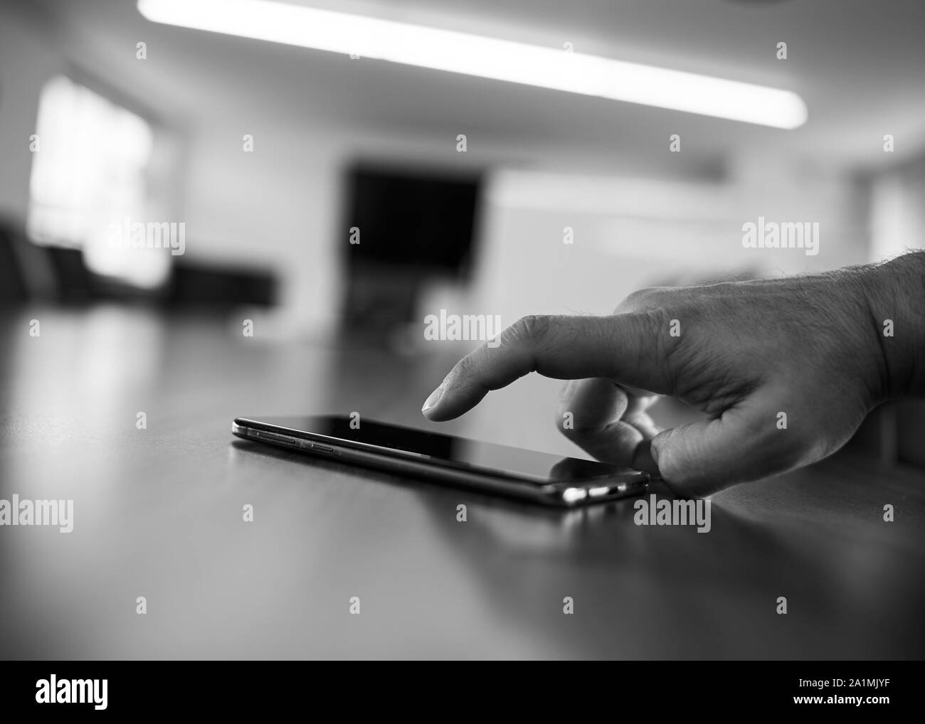 Un homme de race blanche part à l'aide d'un smartphone noir dans un bureau salle de réunion salle de réunion. Banque D'Images