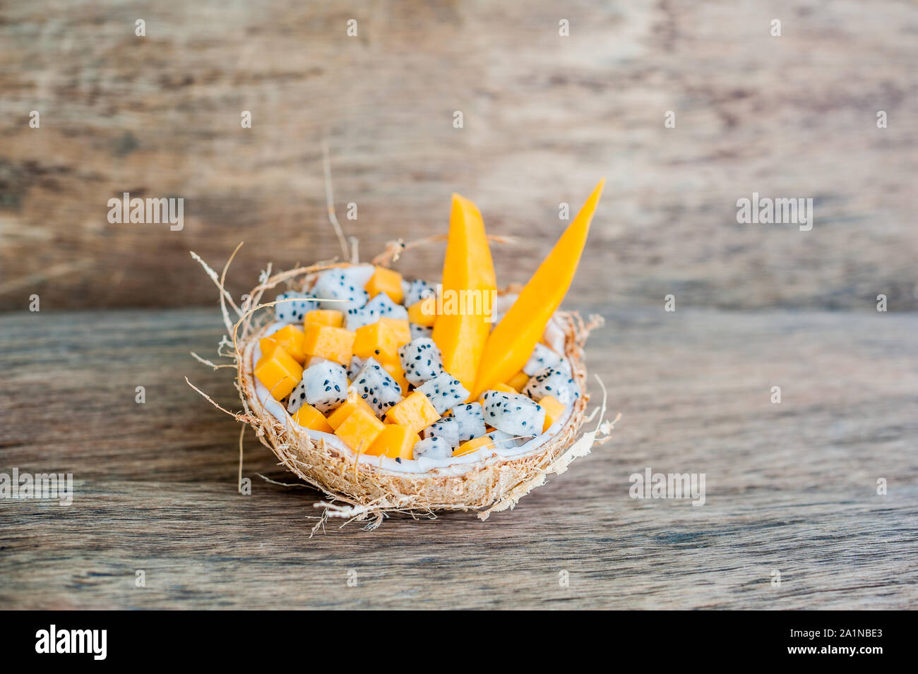 Salade de fruits avec fruits de dragon et papaye en demi noix de coco Banque D'Images