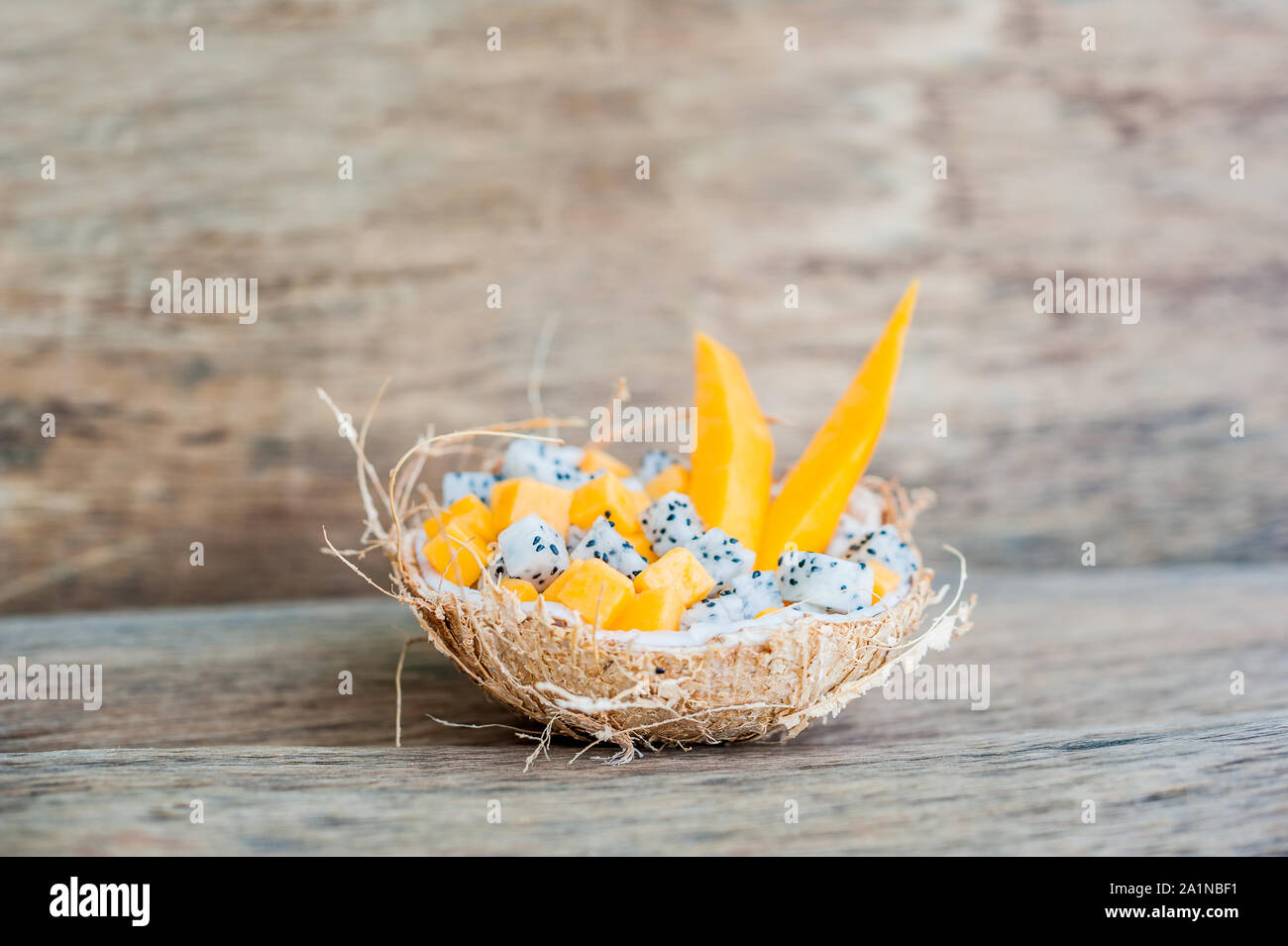 Salade de fruits avec fruits de dragon et papaye en demi noix de coco Banque D'Images