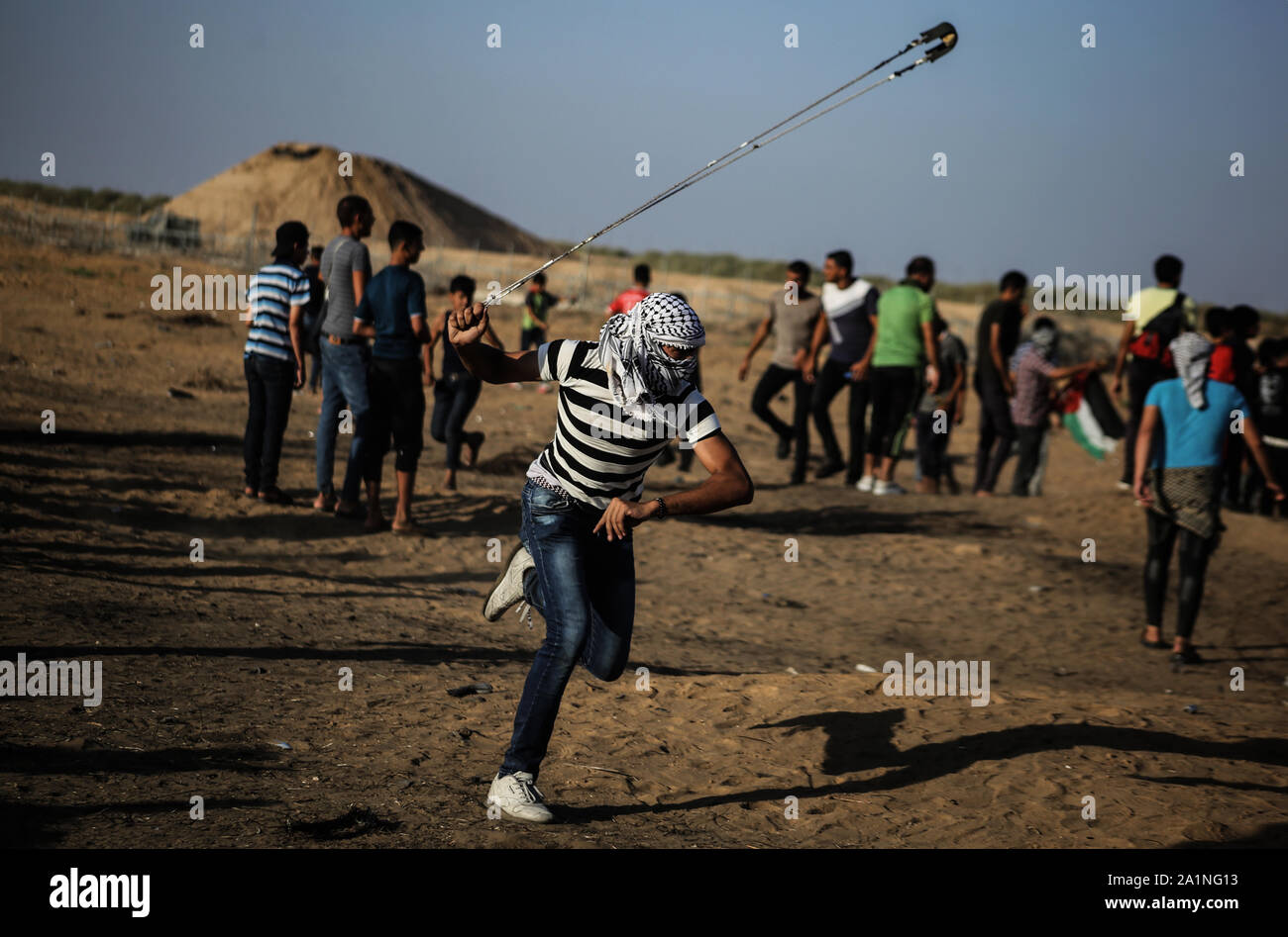 Gaza, la Palestine. 27 Sep, 2019. Un manifestant palestinien utilise une fronde pour lancer des pierres au cours d'une manifestation exigeant la fin de l'asphyxie siège sur la bande de Gaza pendant des années à la frontière Israel-Gaza clôture dans le sud de la bande de Gaza. Credit : SOPA/Alamy Images Limited Live News Banque D'Images