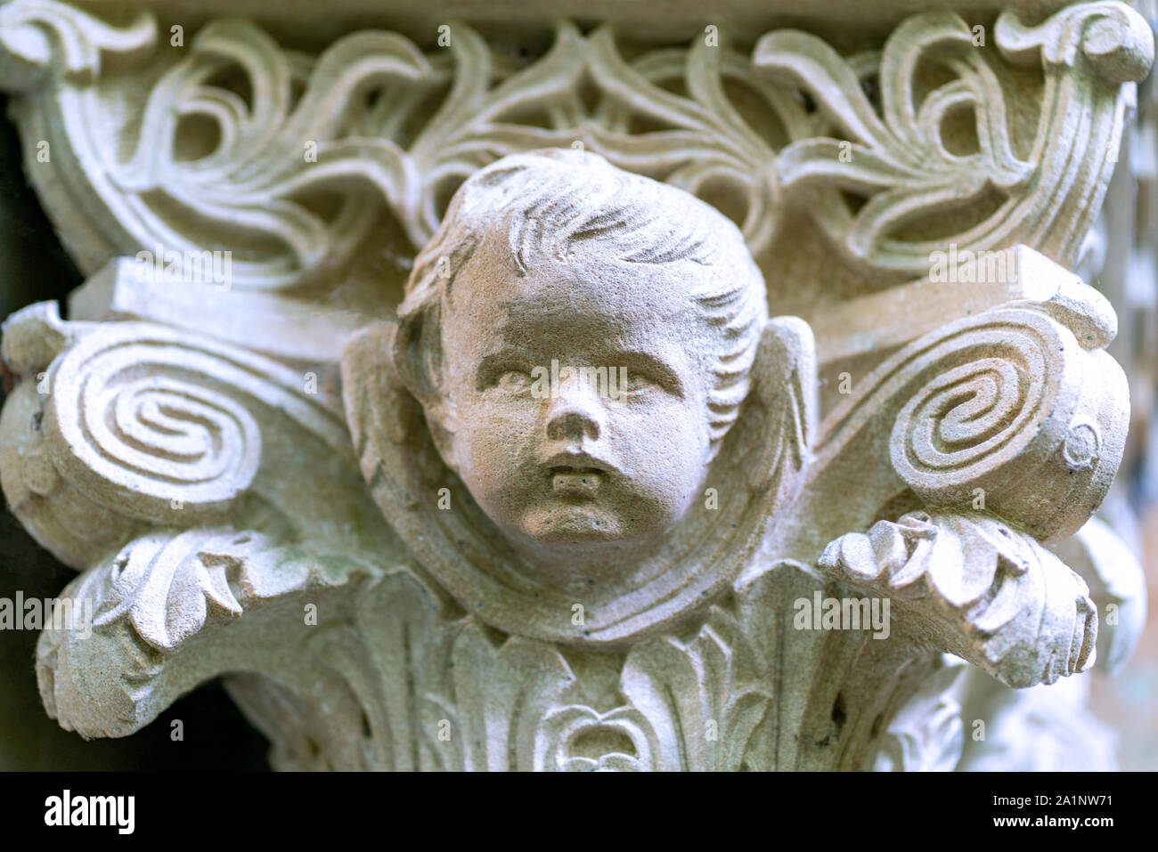 Détail d'une colonne tombe sur un cimetière- tête sculptée d'un petit garçon avec des sculptures symboliques autour de Banque D'Images