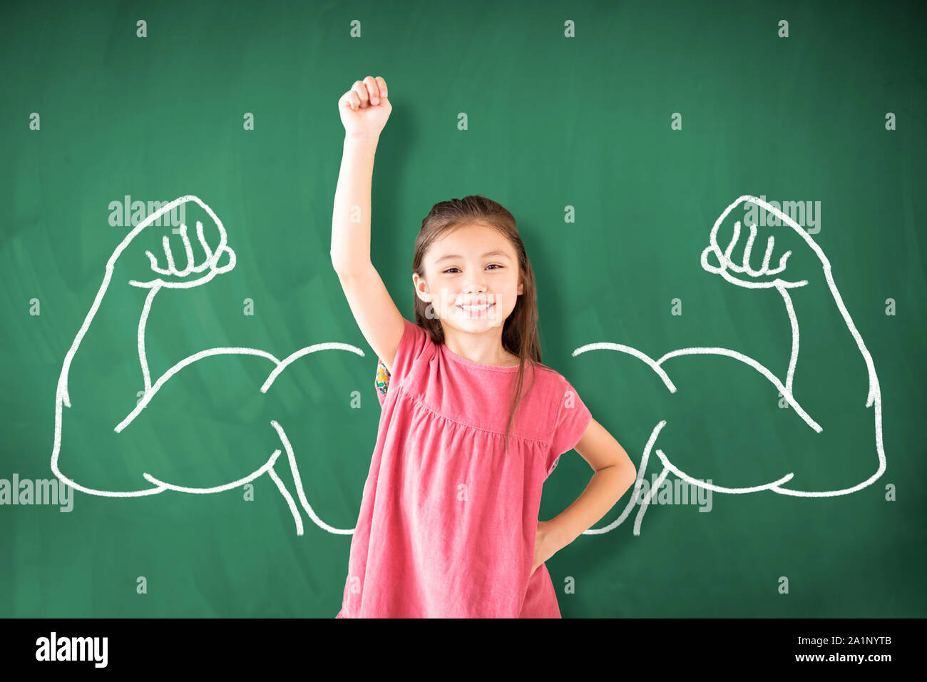 Petite fille debout contre l'ardoise et forte concept gagnant Banque D'Images