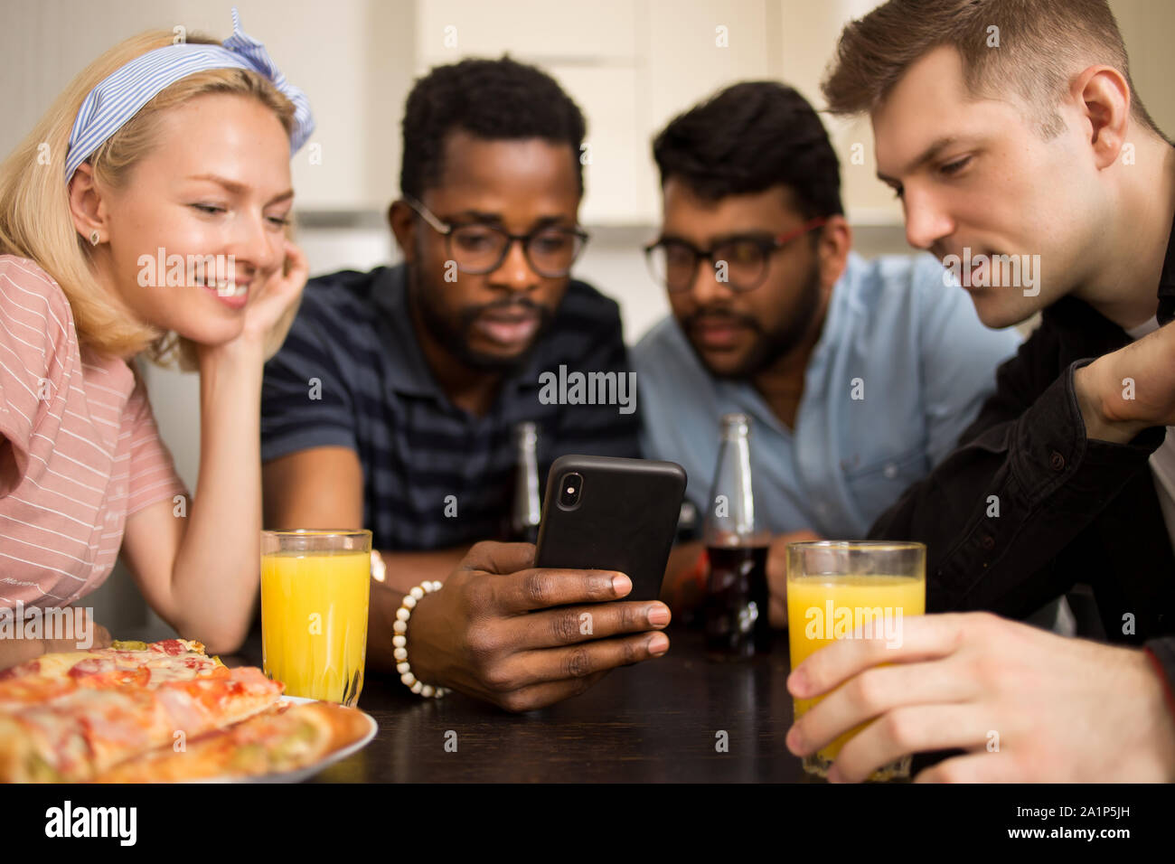 Des amis à l'aide de gadget pendant le déjeuner, manger des pizzas, regardant la vidéo sur smartphone, la lecture de publications sur les réseaux sociaux, faisant appel vidéo ensemble, assis à tabl Banque D'Images