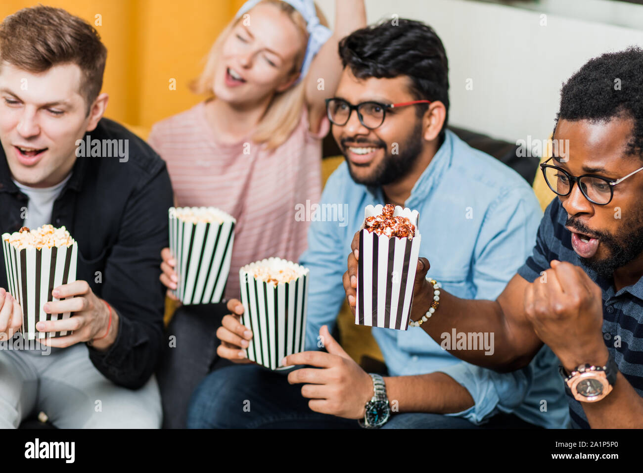 Quatre amis heureux watching sport match en direct, à la télé, eating popcorn et célébrer la victoire. Sport, loisirs, bonheur, enterta Banque D'Images