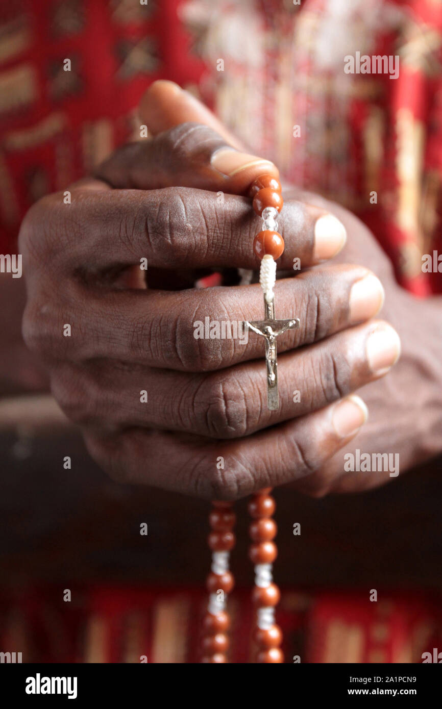 Africain priant dans une église avec un chapelet. Banque D'Images