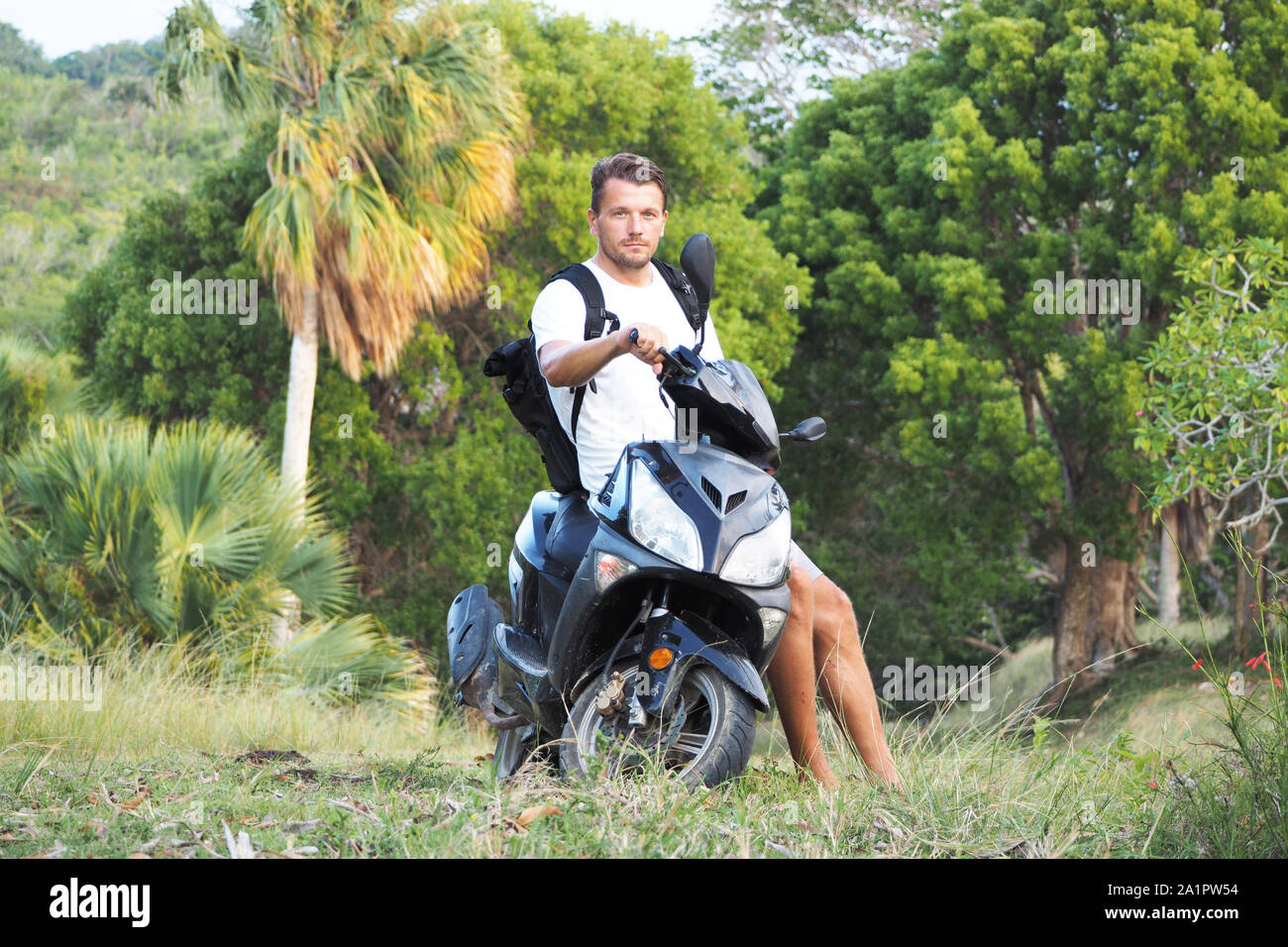 Un homme est assis sur un scooter dans la nature. République dominicaine. Banque D'Images