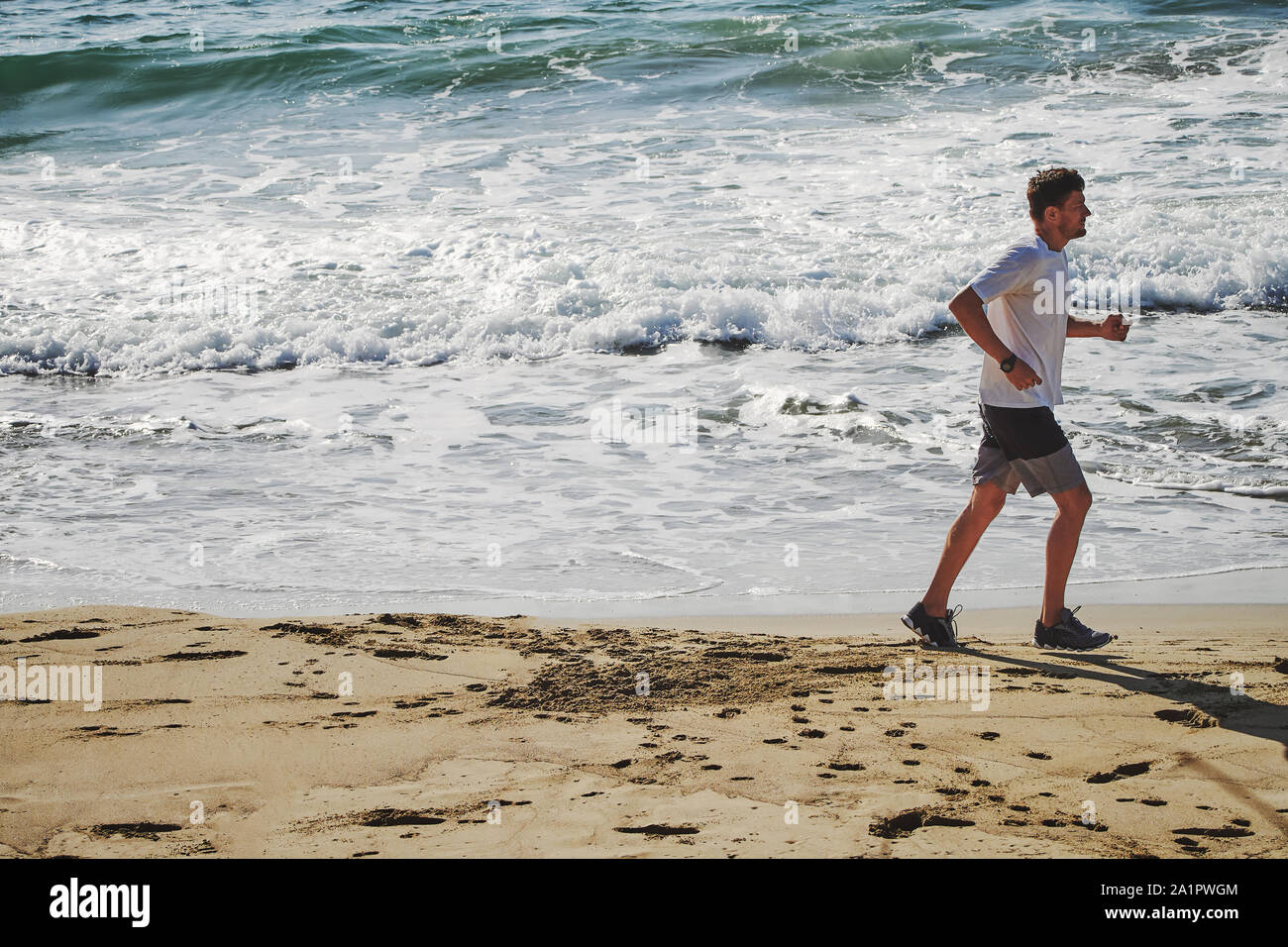 Un homme reprend sa course le long de la côte de l'océan Atlantique. Banque D'Images