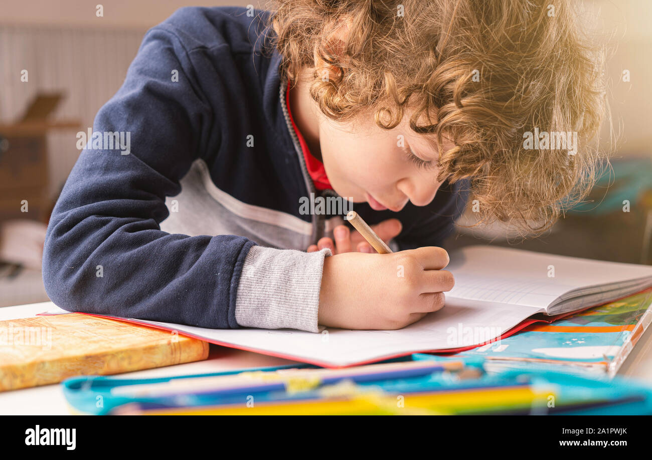 Cute kid écrit sur un cahier dans sa maison. Vie de l'école élémentaire de personnes concept Banque D'Images