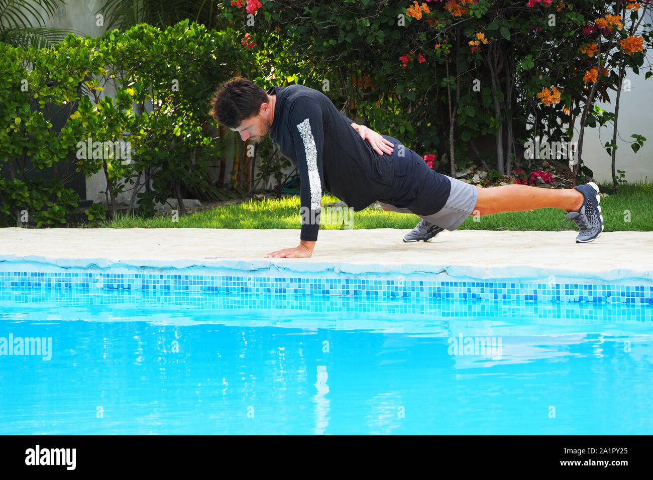 Man doing push-up proche piscine aux beaux jours. Vacances sur une île tropicale. Banque D'Images
