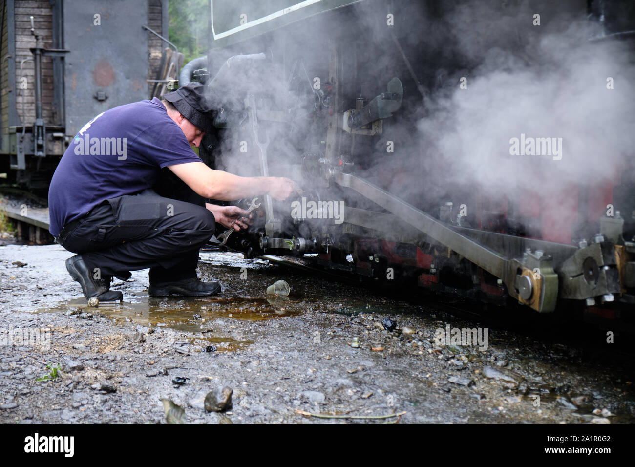 L'homme enveloppé par un moteur à vapeur sur l'ancien train à vapeur à partir de la Roumaine Resita corporation. Banque D'Images