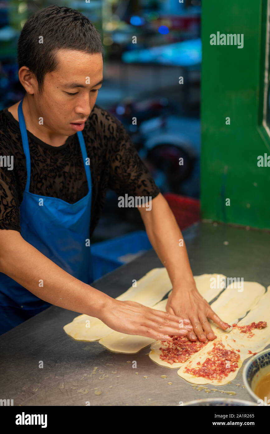 Xian, Chine - Août 2019 : faire de l'homme rempli de viande hachée de bœuf des pâtisseries dans une petite boulangerie locale sur la rue dans le quartier musulman de Xian, ville Banque D'Images