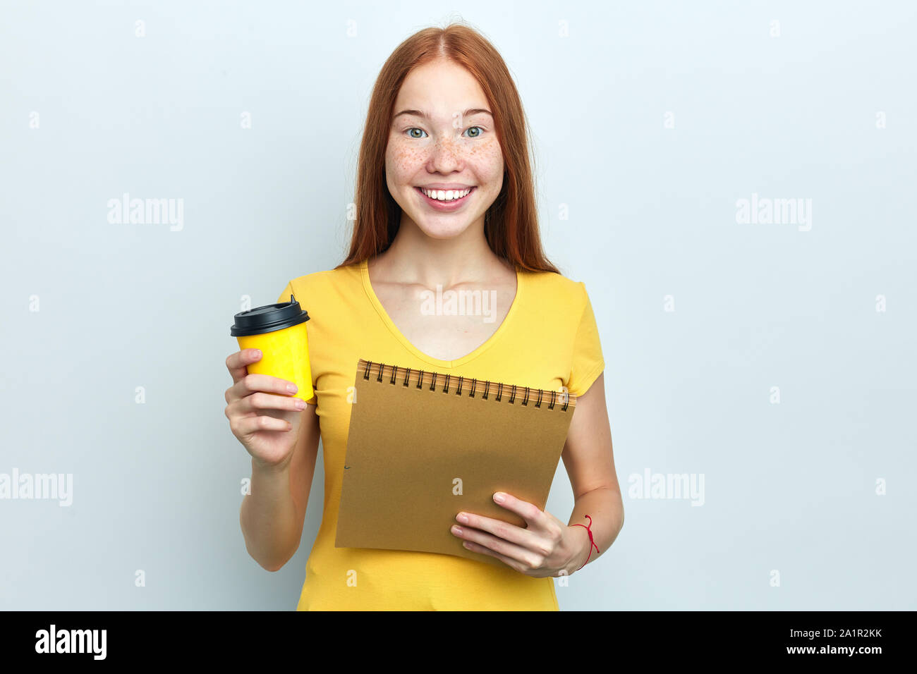 Cheerful girl détient café à emporter et copie d'adresses, étudiant a briser après la tenue d'une conférence. portrait, isolé sur fond blanc, studio sh Banque D'Images