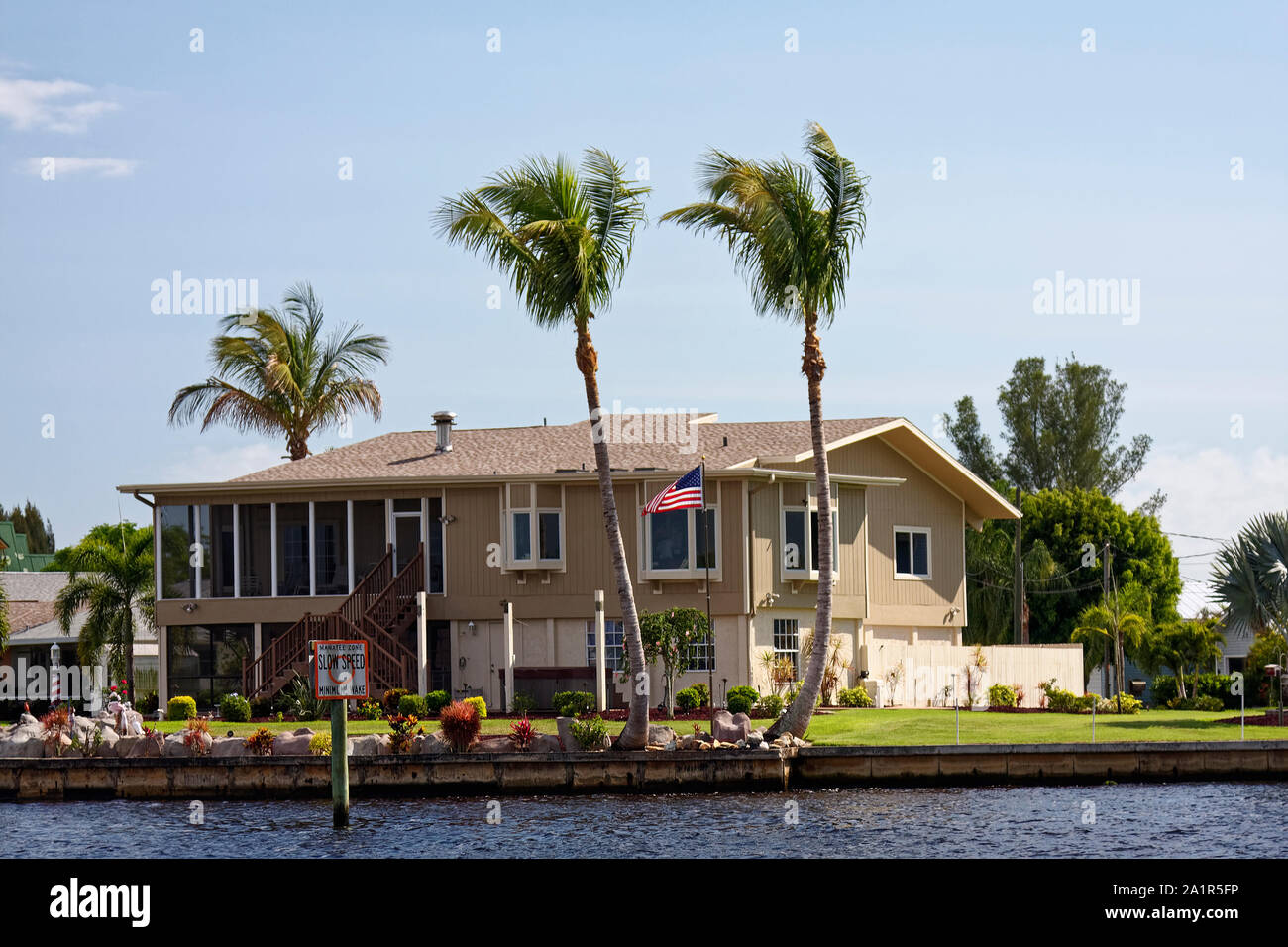 House, Waterfront, la voie fluviale, de 2 étages, pont supérieur, US flag flying, aménagement paysager attrayant, palmiers, sud-ouest de la Floride, FL, spr Banque D'Images