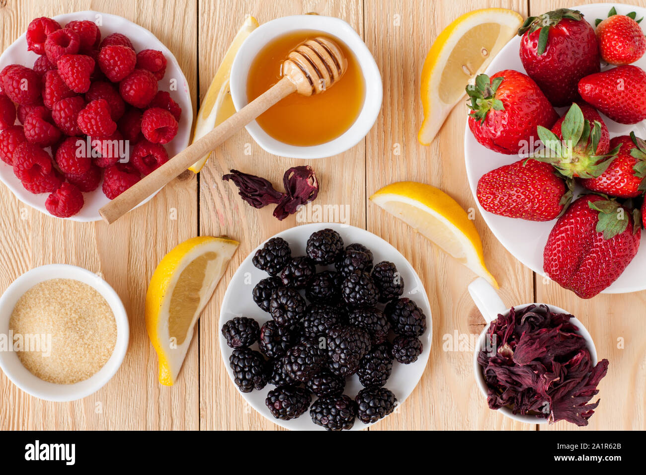 Framboises, fraises, mûres, de miel, de citron, de gélatine, de fleurs d'hibiscus séchées. Préparation de la gelée de fruits terrine aux fruits rouges Banque D'Images