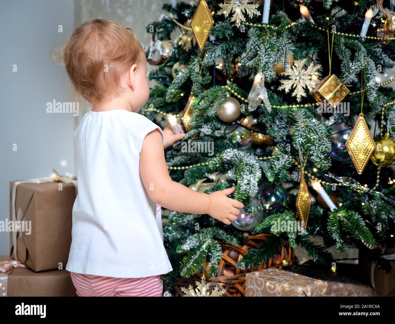 Méconnaissable petit bébé touche décoration d'arbre de Noël. Mignon bébé fille 2 ans décore l'arbre de Noël Banque D'Images