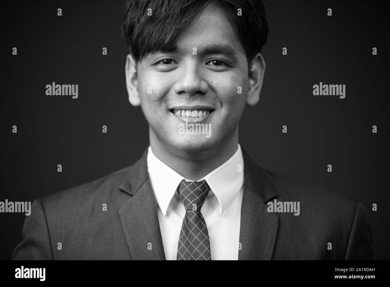 Young handsome Asian businessman smiling portrait tourné en noir et blanc Banque D'Images