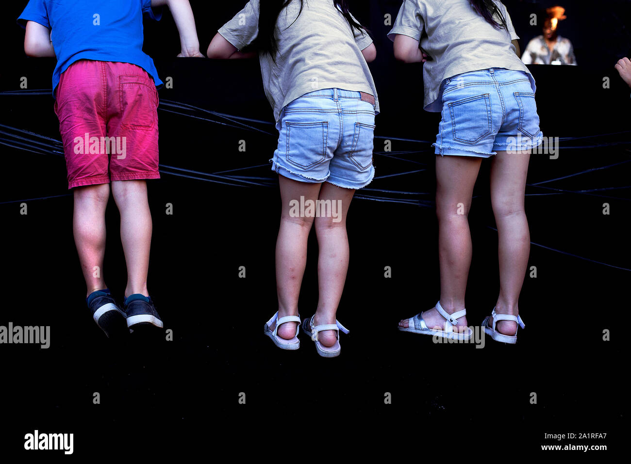 Les enfants grimper sur une scène pour regarder un spectacle. Banque D'Images