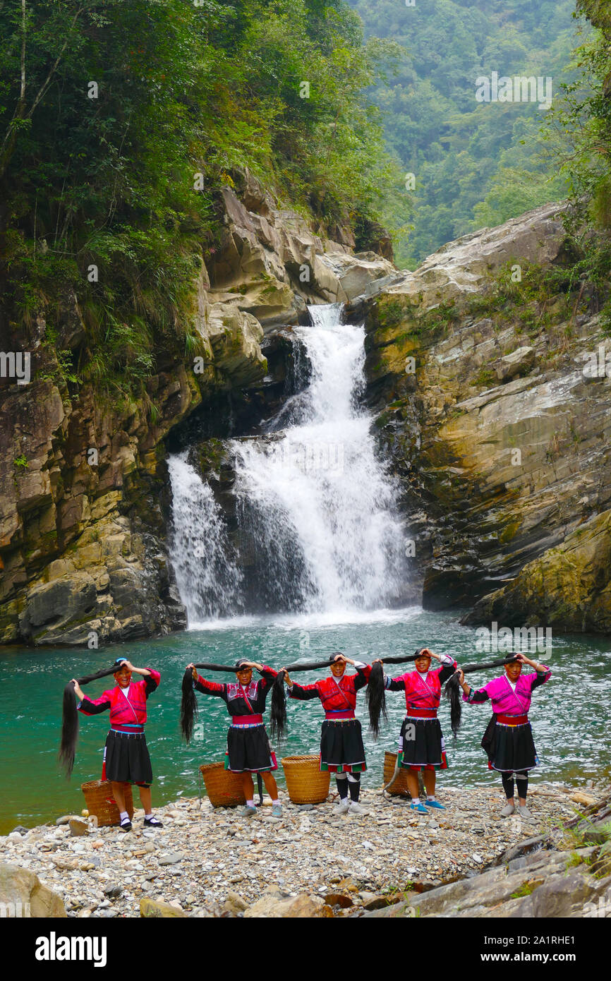 Les cheveux longs, les femmes des minorités ethniques Yao posant devant une chute d'eau dans la zone Longsheng Rizières en terrasses dans Ghuangxi Zhuang Région autonome de Chine, proche de G Banque D'Images
