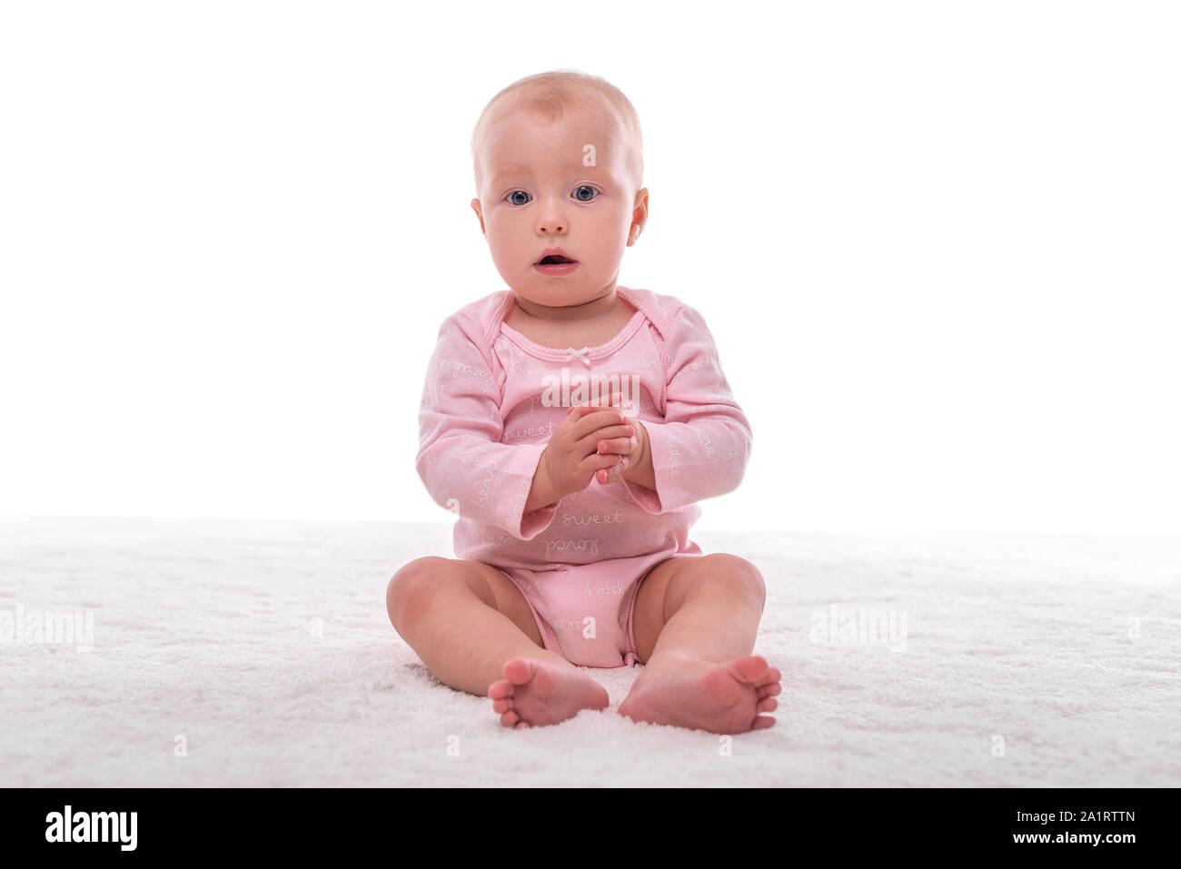 Petite fille sur un tapis blanc dans une pièce lumineuse. Banque D'Images