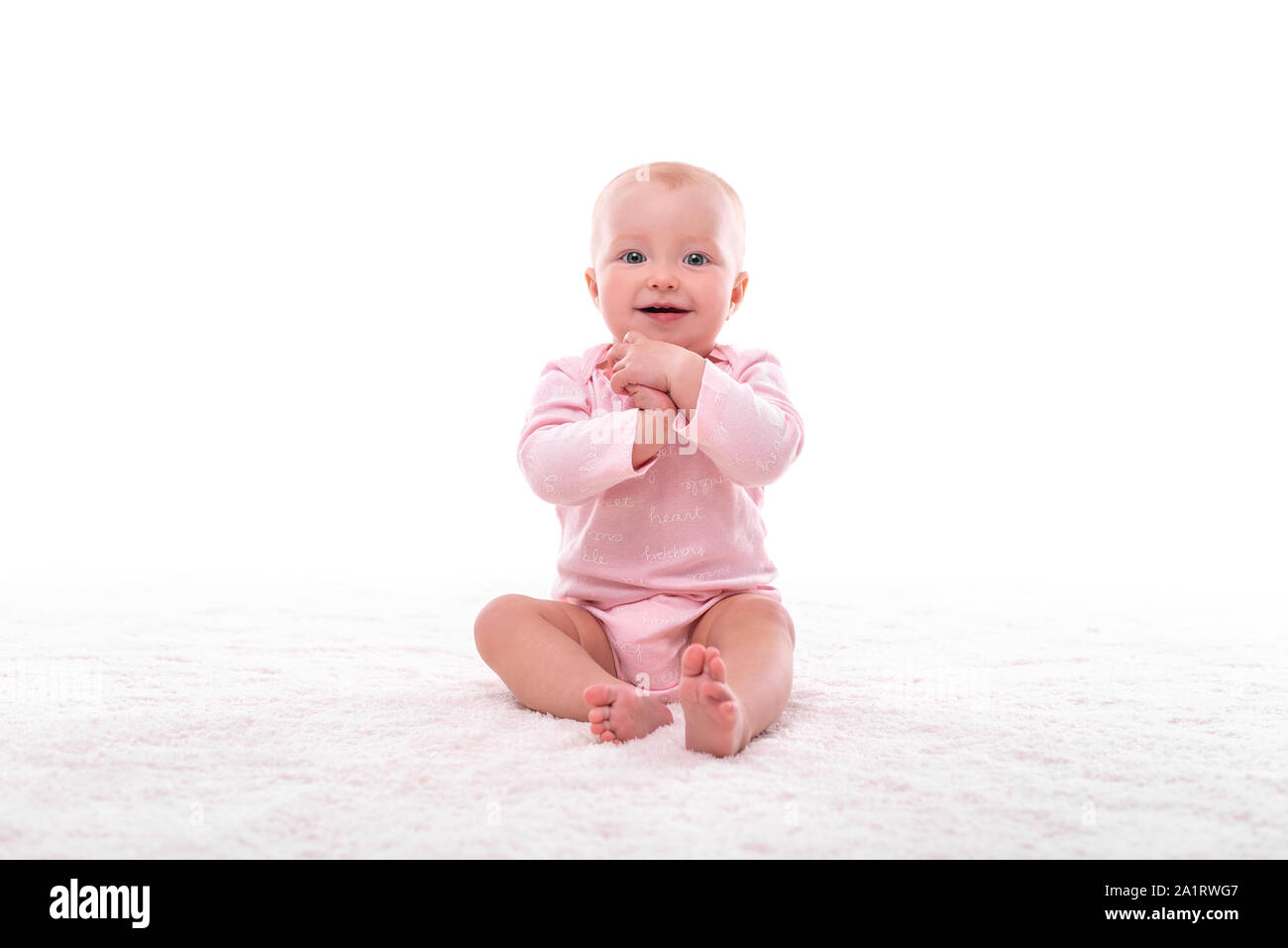 Petite fille sur un tapis blanc dans une pièce lumineuse. Banque D'Images