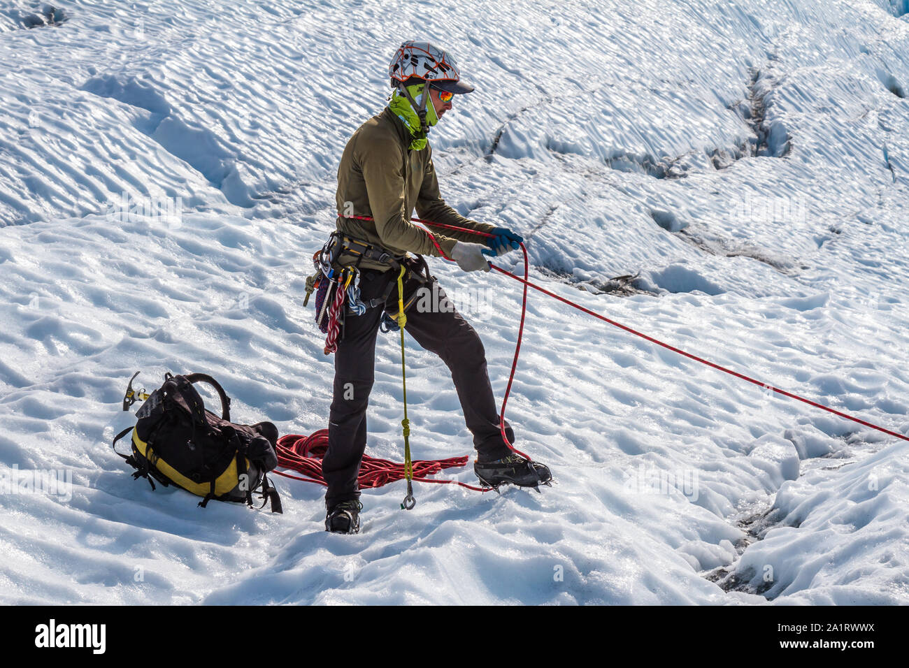 Guide sur le Glacier Matanuska en Alaska aide un client avec un corps l'assurage sauvegardés avec une broche à glace l'ancre. Banque D'Images