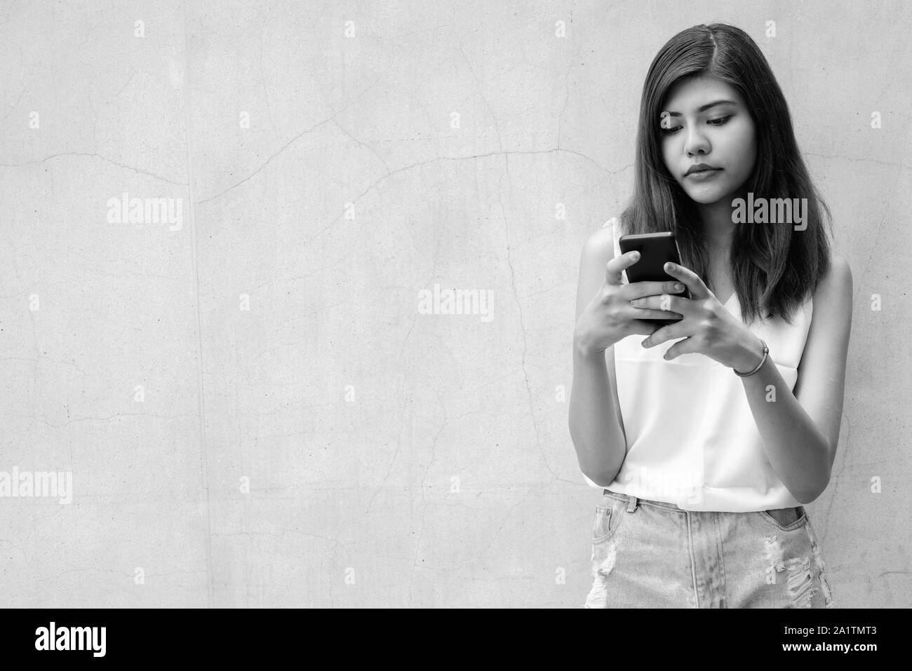 Belle jeune fille adolescente et de l'envoi de message sms avec mobile phone outdoors Banque D'Images