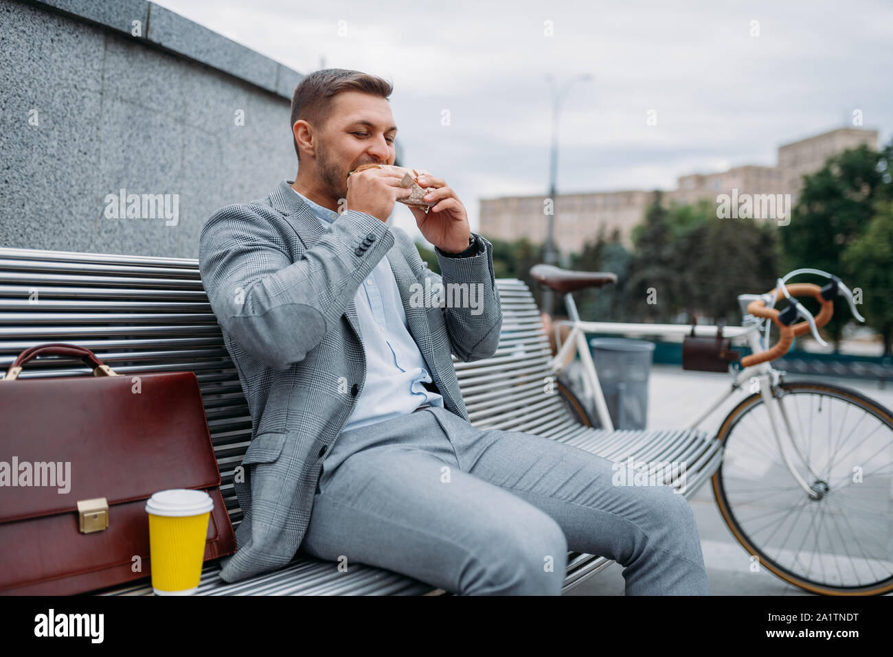 Businessman with bike mange à midi sur le banc Banque D'Images