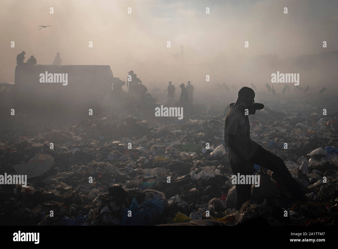 Un homme protège son visage de la fumée dans le dépotoir de Dandora détritus dans le Nairobi, Kenya, le 18 février 2018. Banque D'Images