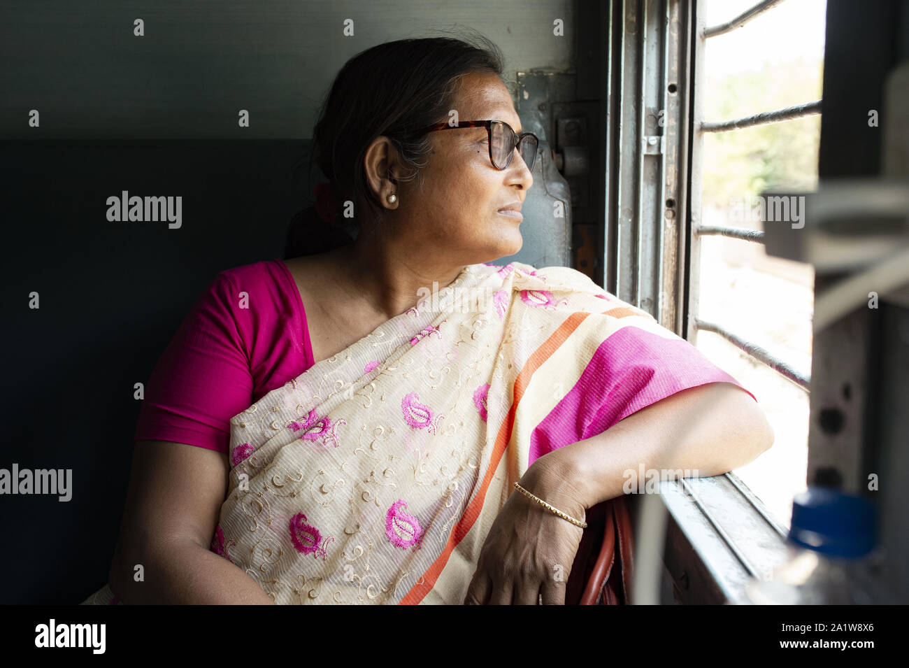 Une femme indienne est en regardant par la fenêtre d'un train indien alors qu'elle voyage de New Delhi à Varanasi. Banque D'Images