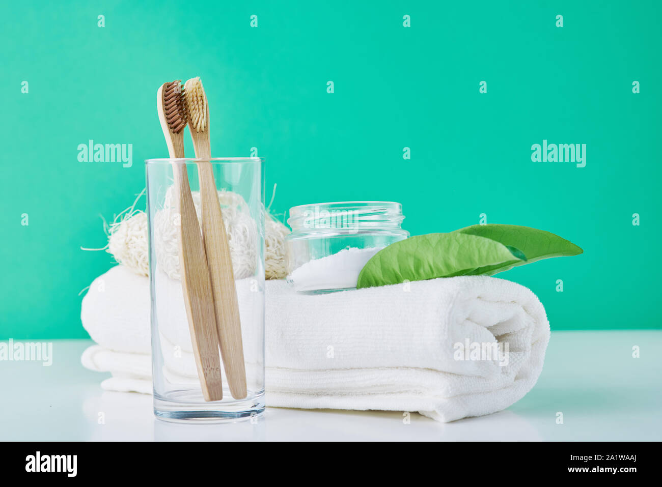 Bambou en bois des brosses à dents en verre, le bicarbonate de soude et serviette sur fond vert. Concept d'hygiène personnelle Banque D'Images