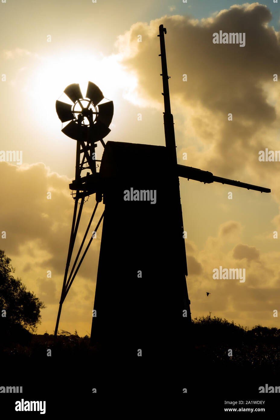 Drainage gazon Fenn Mill de l'autre côté de la rivière comme une silhouette avec le soleil derrière elle. Banque D'Images