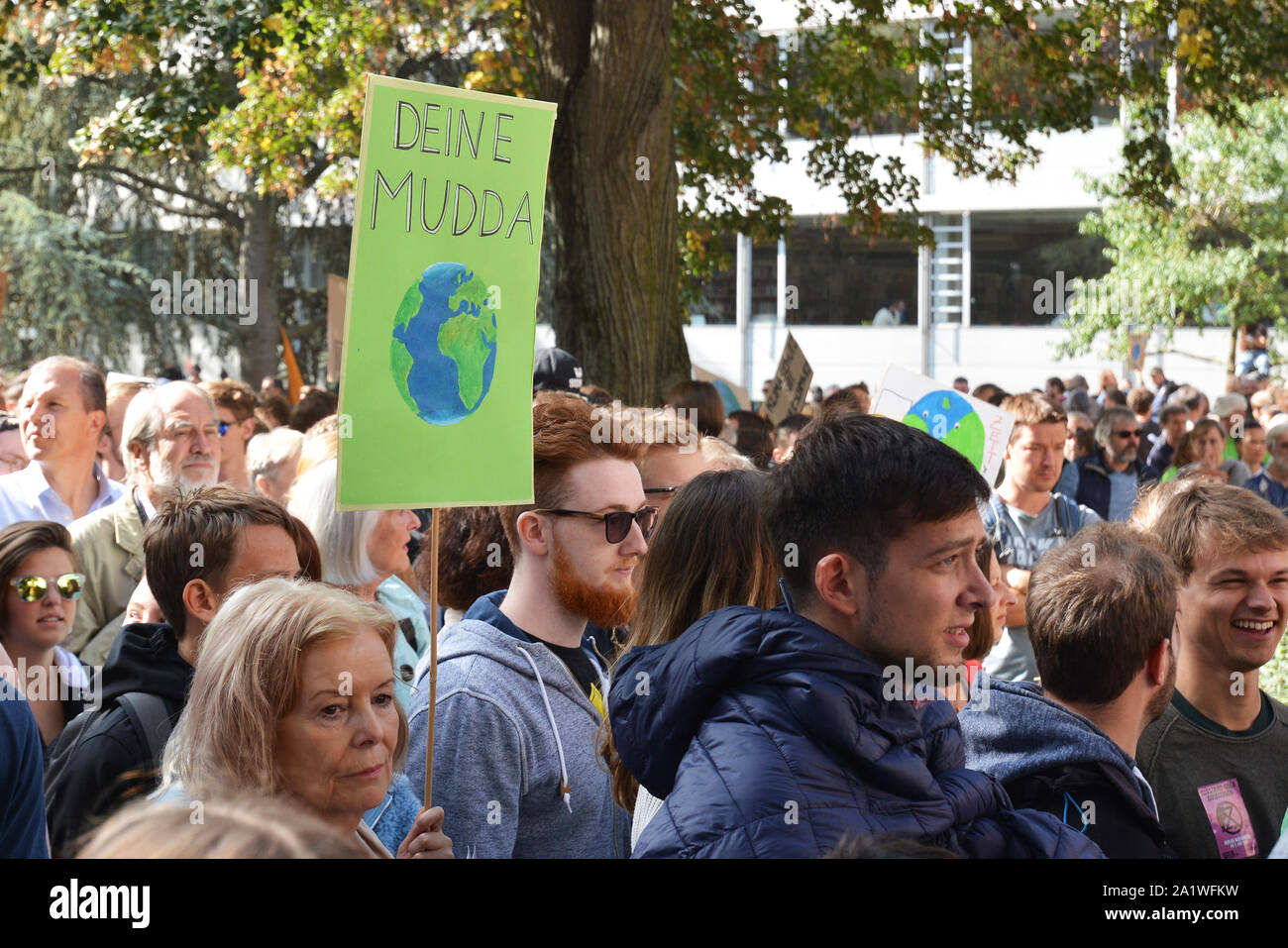 Signe de protestation disant 'ta mère' en argot allemand et montrant la planète Terre tenu par femme pendant les changements climatiques mondiaux / grève vendredi pour les futures Banque D'Images