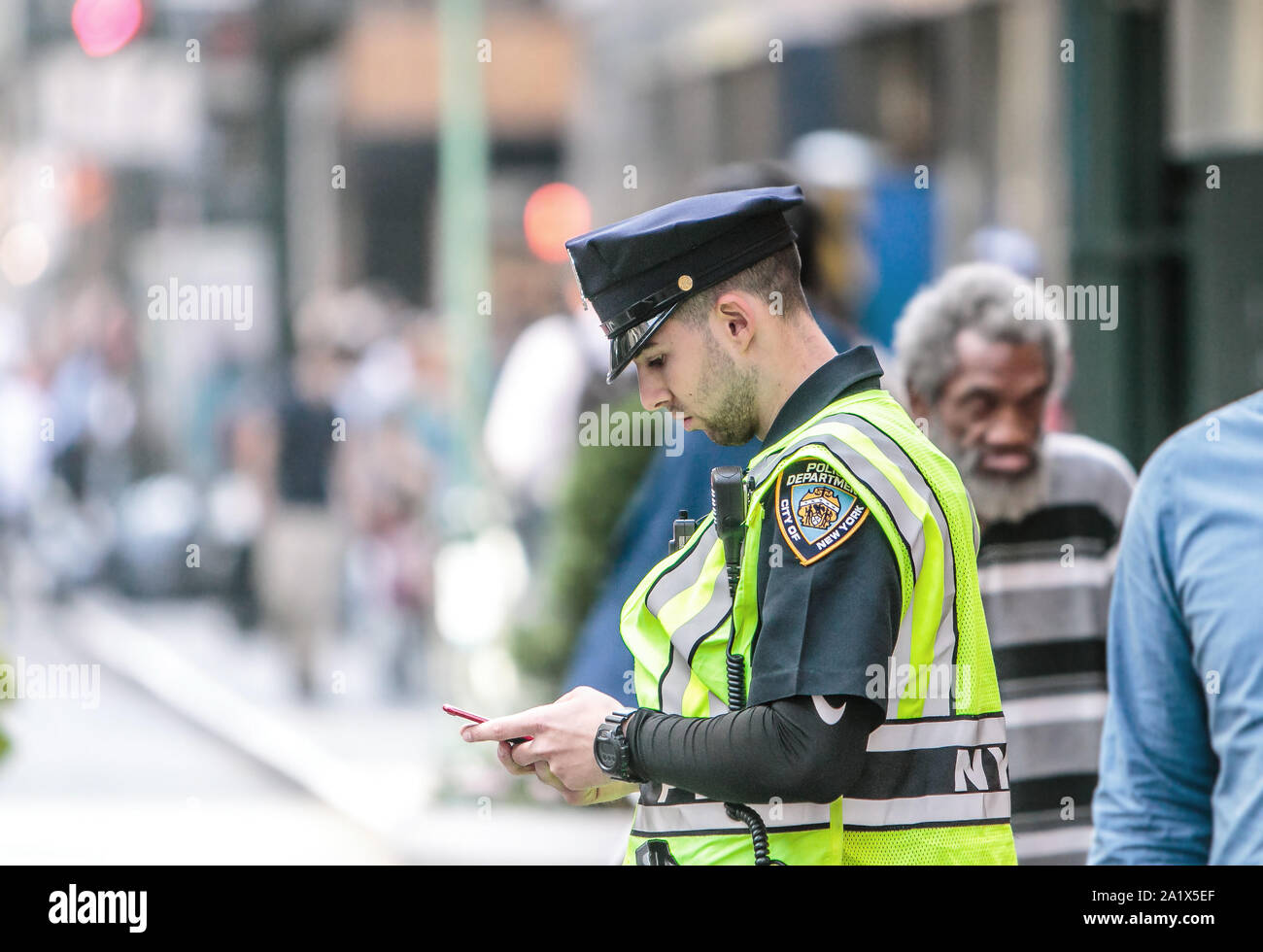 New York, 9/27/2019 : officier de la police de contrôler son téléphone alors que c'est manning les rues de Manhattan. Banque D'Images