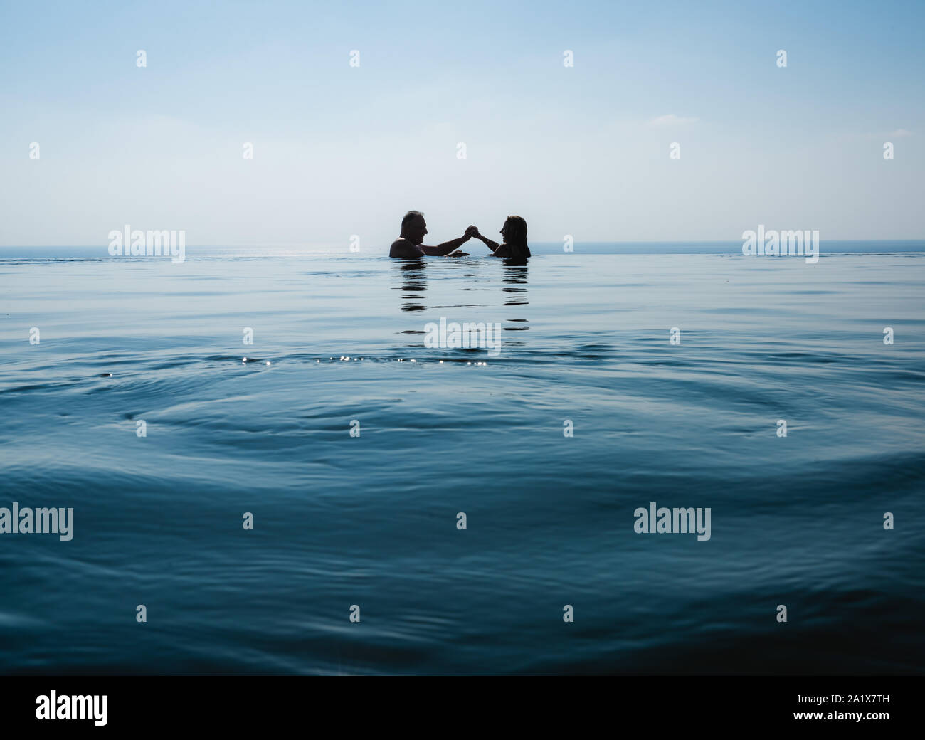 C'est couple swimming in pool contre belle mer bleu Banque D'Images